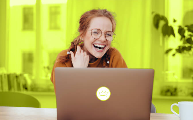Ein fröhlich lächelnde Frau sitzend vor einem Laptop